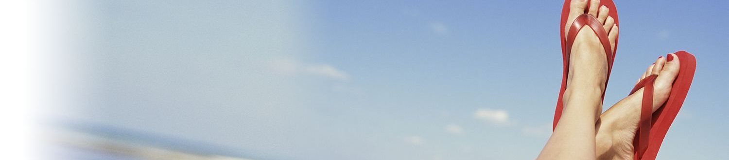 Feet in red flip flops with blue sky in background