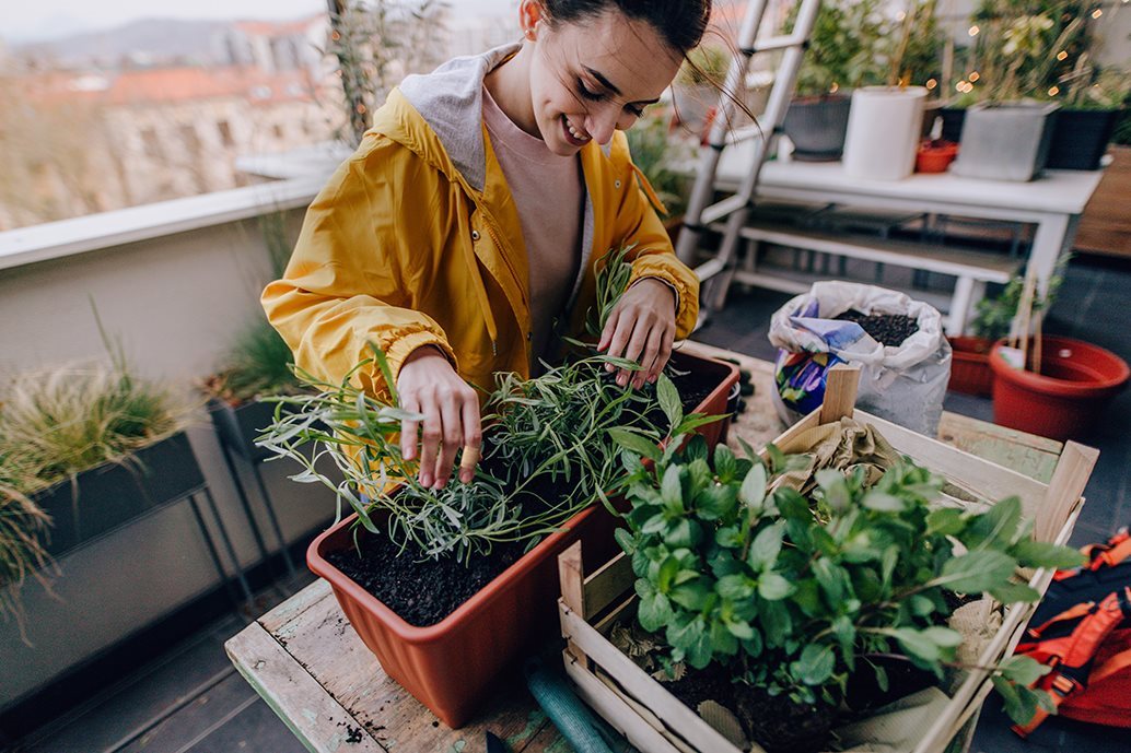 Νεαρή γυναίκα κάνει κηπουρική στο μπαλκόνι