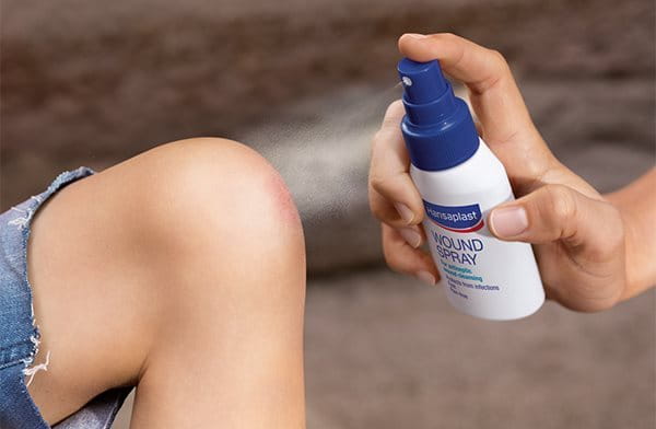 Hansaplast wondspray wordt gespoten op een bezeerde knie