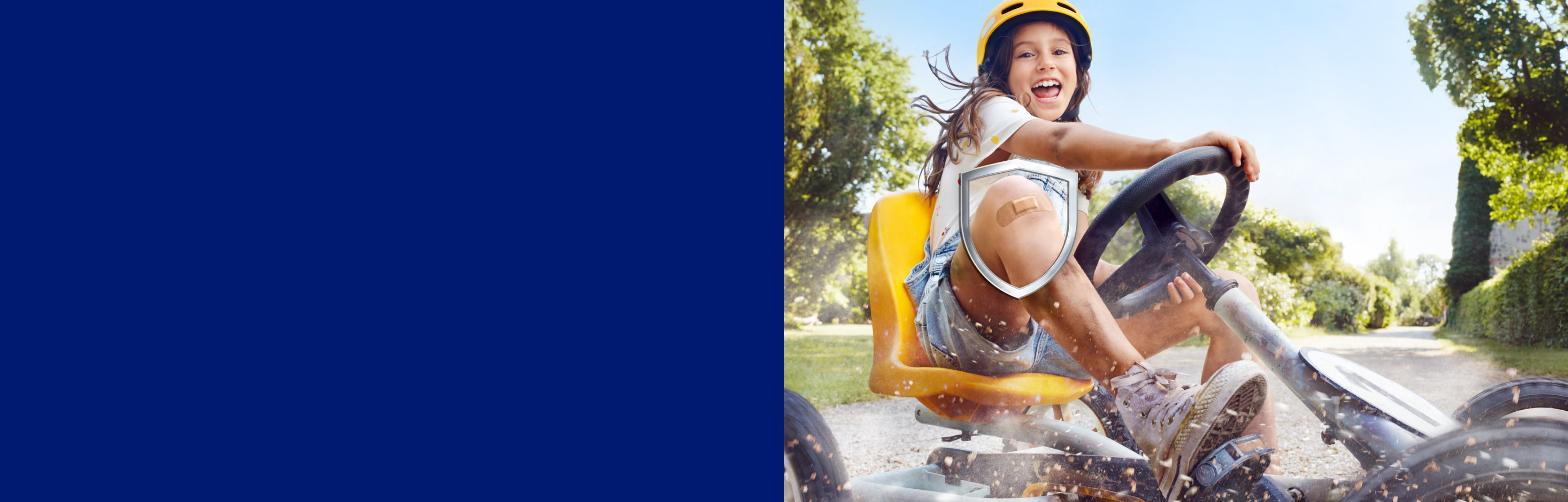 A girl has fun riding a go kart, on her knee a Hansaplast Elastic Plaster.