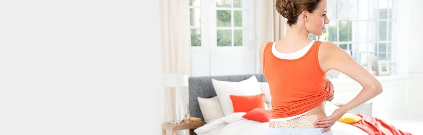 Frau trägt ABC Wärme-Pflaster unter Kleidung