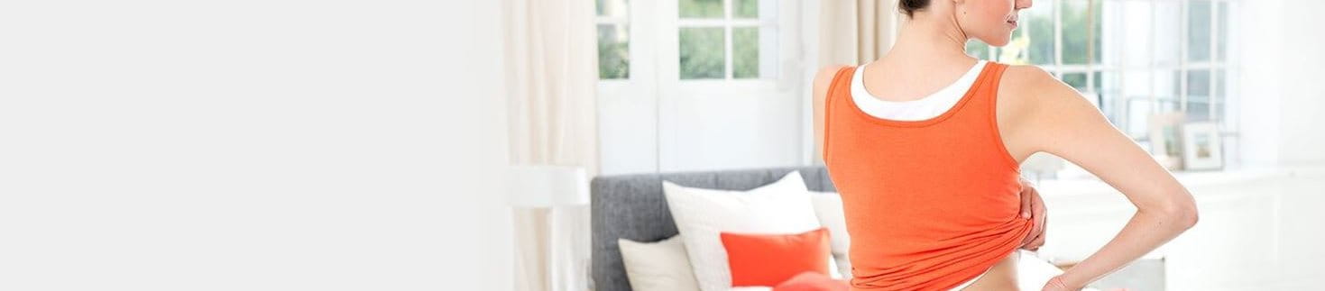 Frau trägt ABC Wärme-Pflaster unter Kleidung