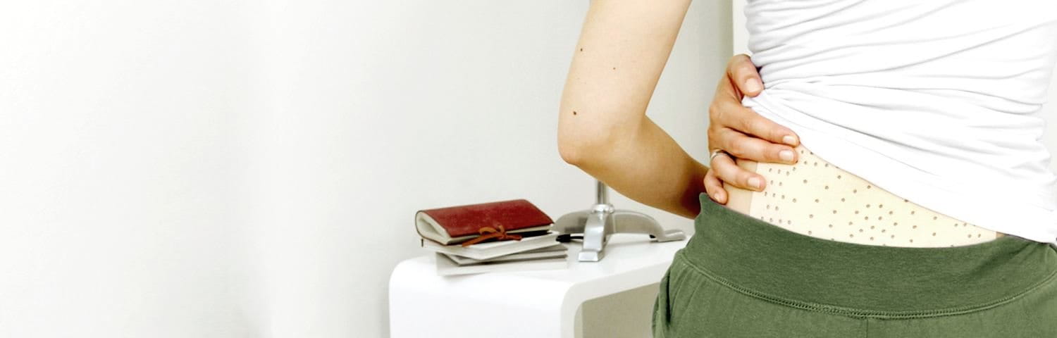 Frau trägt ABC Wärme-Pflaster unter Kleidung