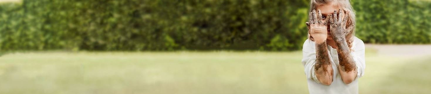 Kind hält schmutzige Hände vors Gesicht