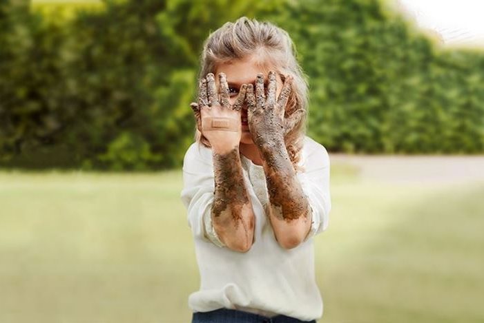 Kind hält sich schmutzige Hände vors Gesicht