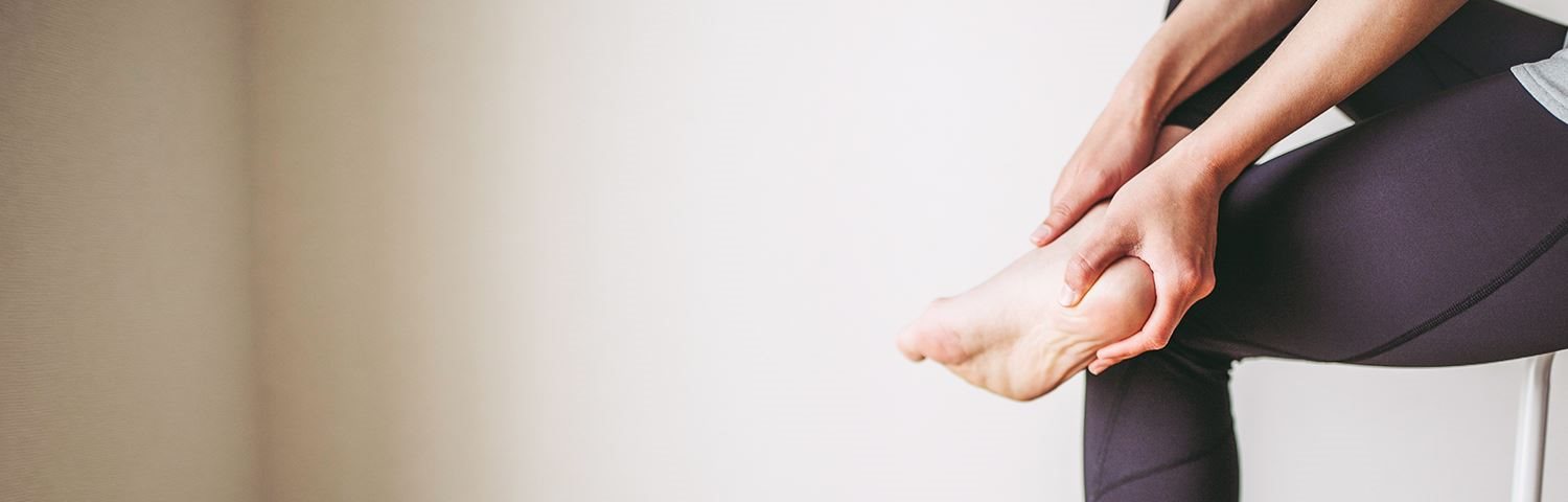 Ein Mann, der schmerzerfüllt seinen Fuß mit Fersensporn betrachtet.