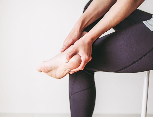 Ein Mann, der schmerzerfüllt seinen Fuß mit Fersensporn betrachtet.