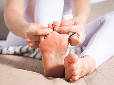 Frau greift an ihre Zehen