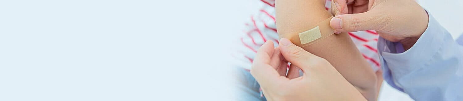 Jemand klebt ein Pflaster auf den Ellbogen eines Kindes