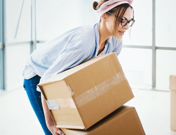 Frau hebt Gegenstand rückenschonend