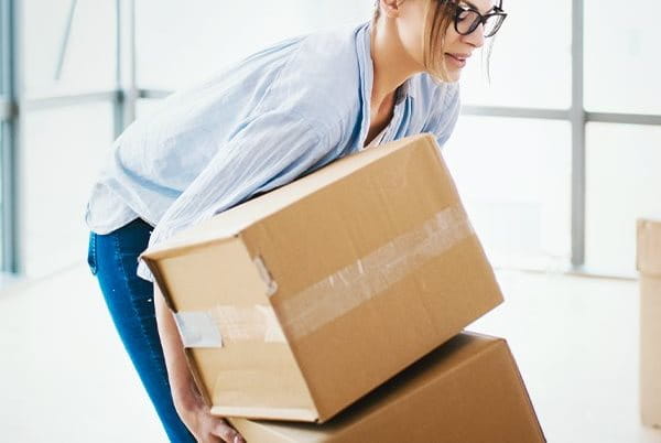 Frau hebt Gegenstand rückenschonend