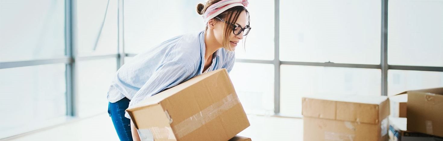 Frau hebt Gegenstand rückenschonend