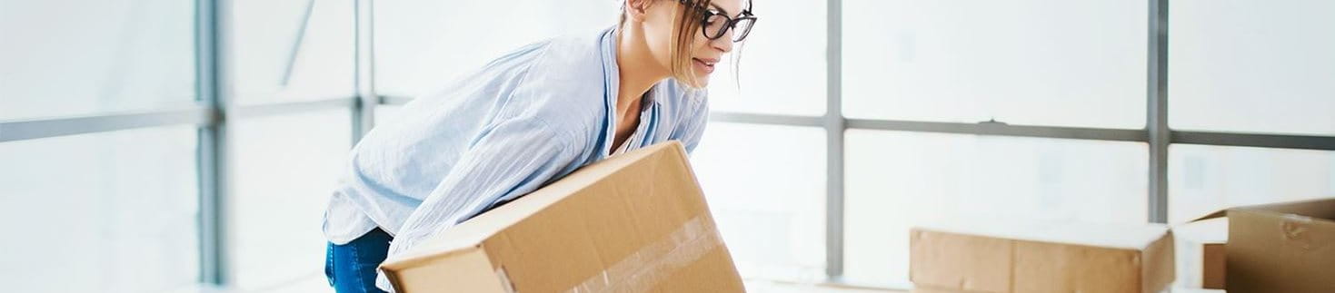 Frau hebt Gegenstand rückenschonend