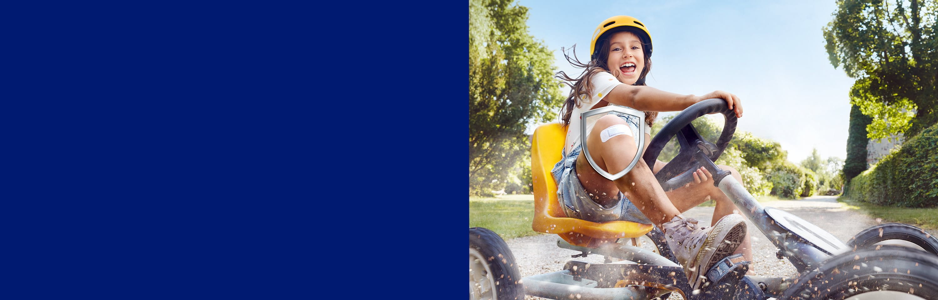 Ein Mädchen mit einem Pflaster auf ihrem Knie fährt mit einem Kettcar.