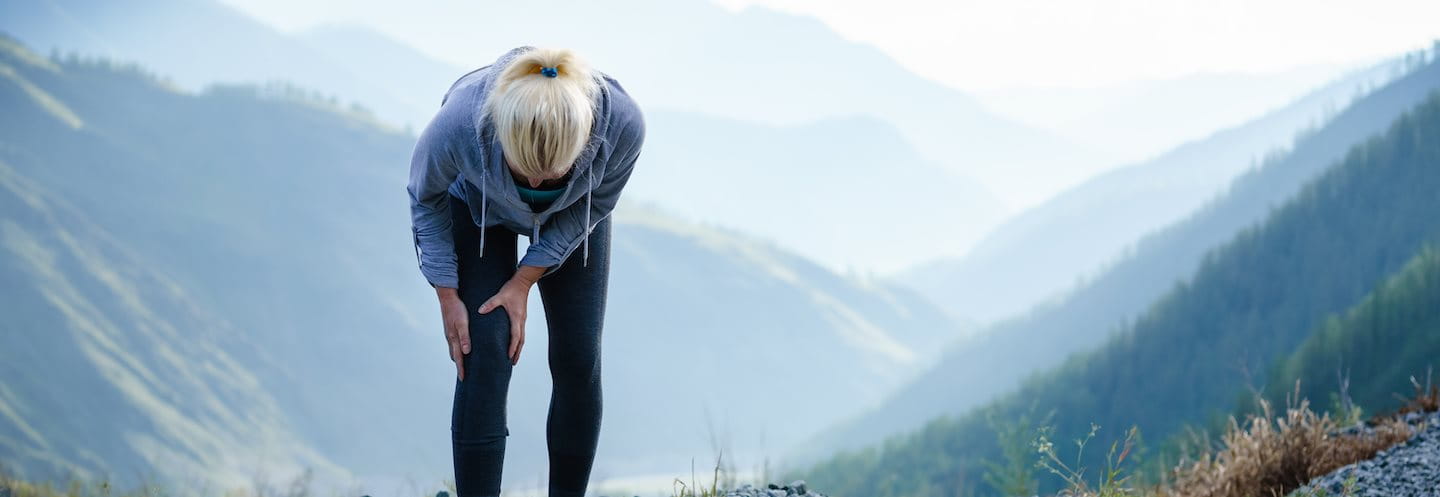 Eine Joggerin hält sich vor Schmerzen das Knie fest