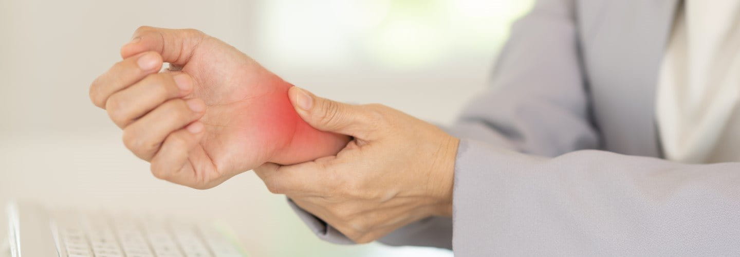 Frau drückt auf ihr schmerzendes Handgelenk