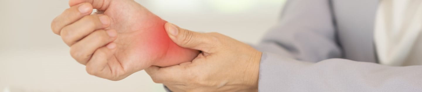 Frau drückt auf ihr schmerzendes Handgelenk