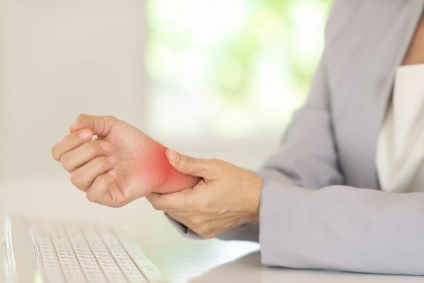 Frau drückt auf ihr schmerzendes Handgelenk