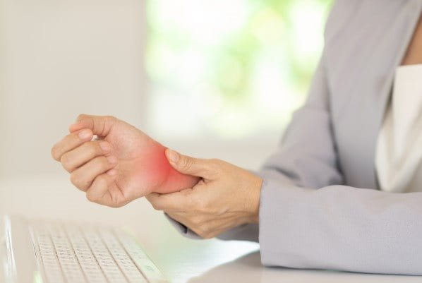 Frau drückt auf ihr schmerzendes Handgelenk