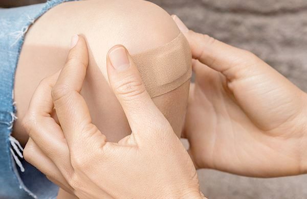 Kind bekommt Pflaster auf seine Schürfwunde geklebt