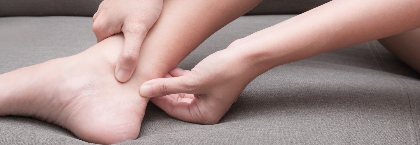 Eine Frau fühlt Schmerzen in der Achillessehne