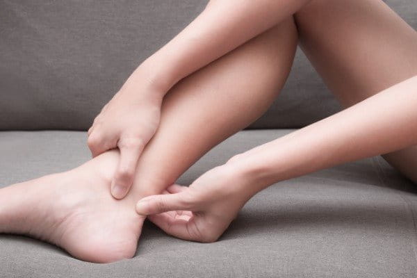 Eine Frau fühlt Schmerzen in der Achillessehne