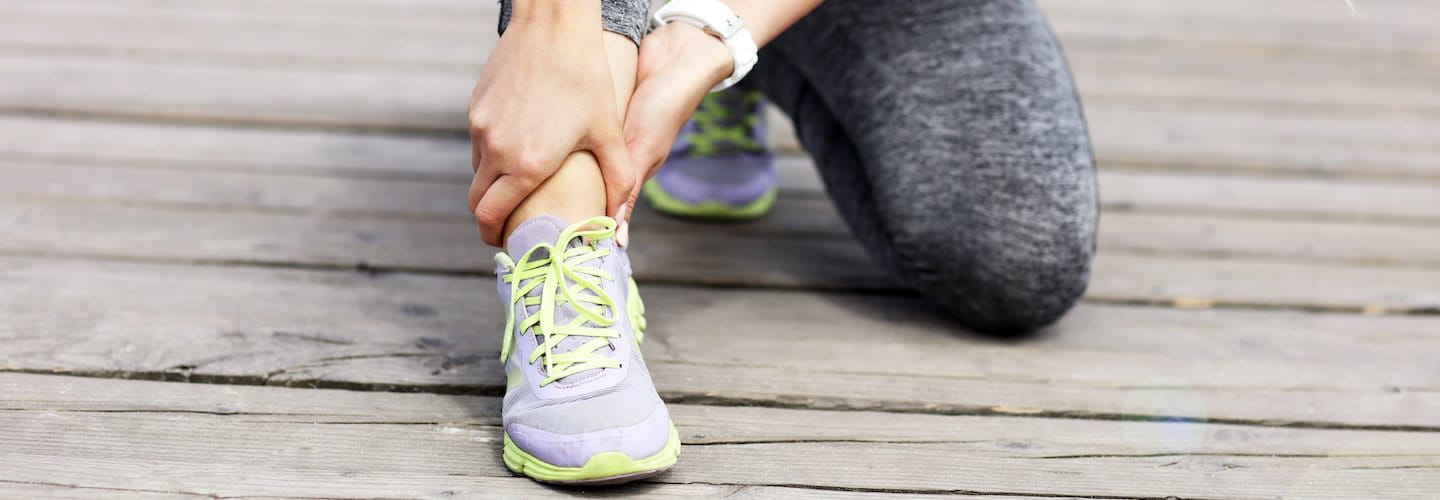 Junge Frau hält sich das schmerzende Fußgelenk