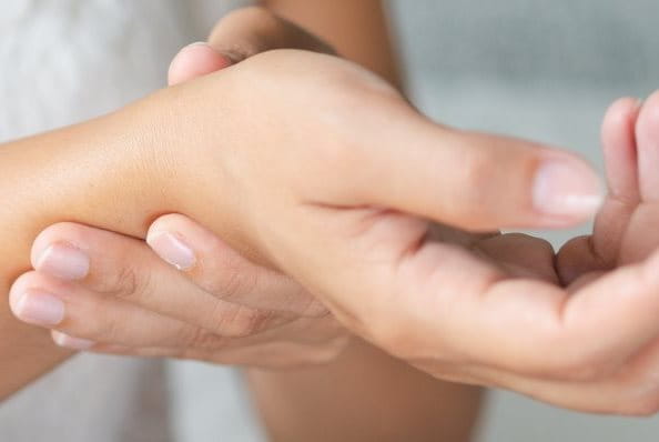 Frau mit Handgelenk Schmerzen hält sich ihre Hand