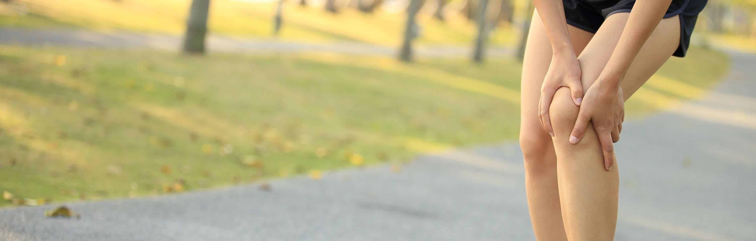 Läuferin hält sich das Knie wegen Knieschmerzen beim joggen