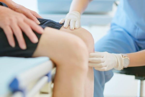 Ärztin untersucht Knie auf Meniskusschaden