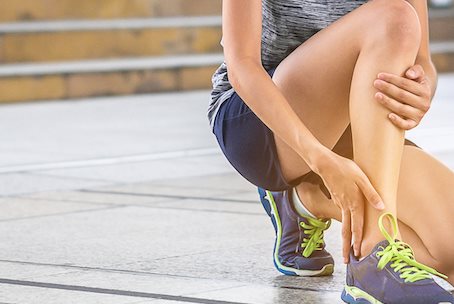Junge Frau tastet Knöchel ab