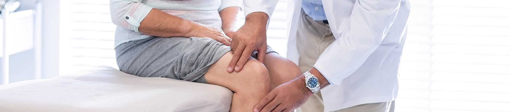 A doctor is diagnosing a woman’s knee