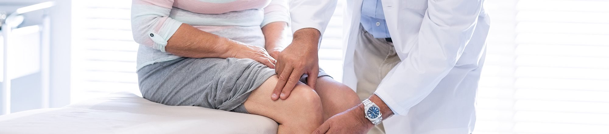 A doctor is diagnosing a woman’s knee