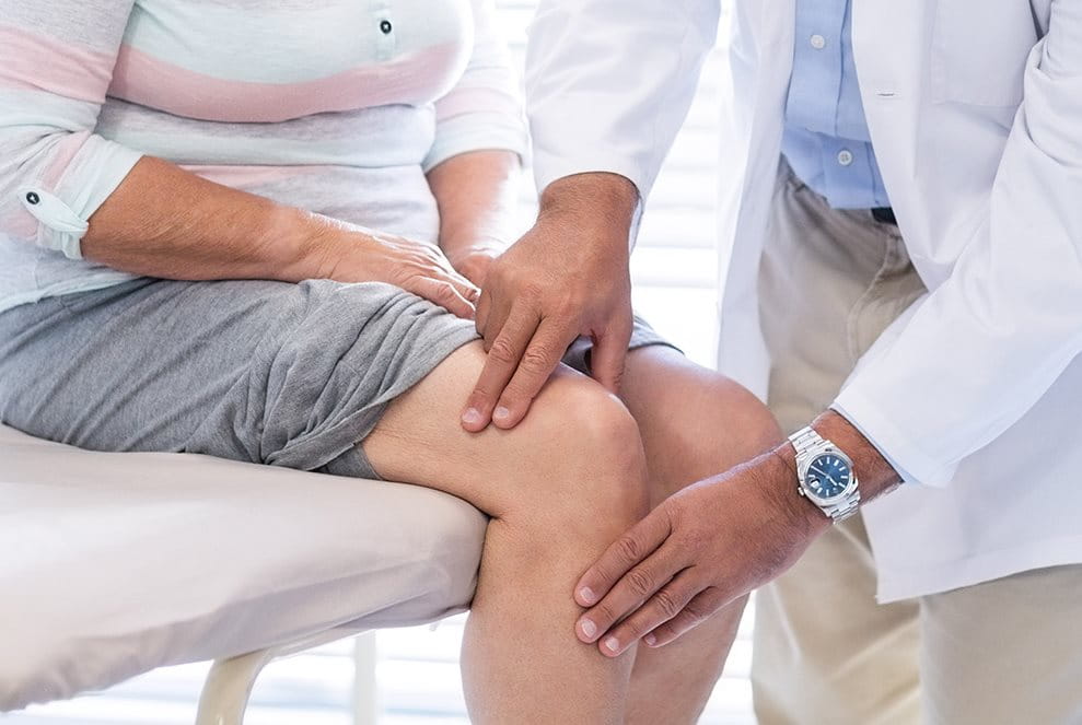 A doctor is diagnosing a woman’s knee
