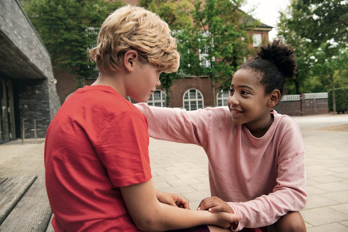 Een jongen en een meisje praten met elkaar op het schoolplein
