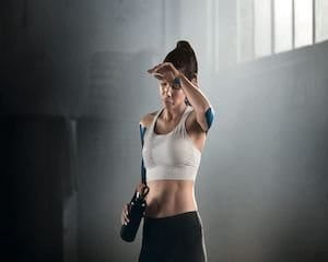 Une femme en tenue de sport se touche le front