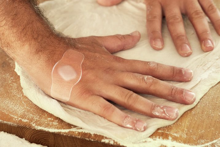 Person kneading dough with a hydrocolloid plaster on their hand.
