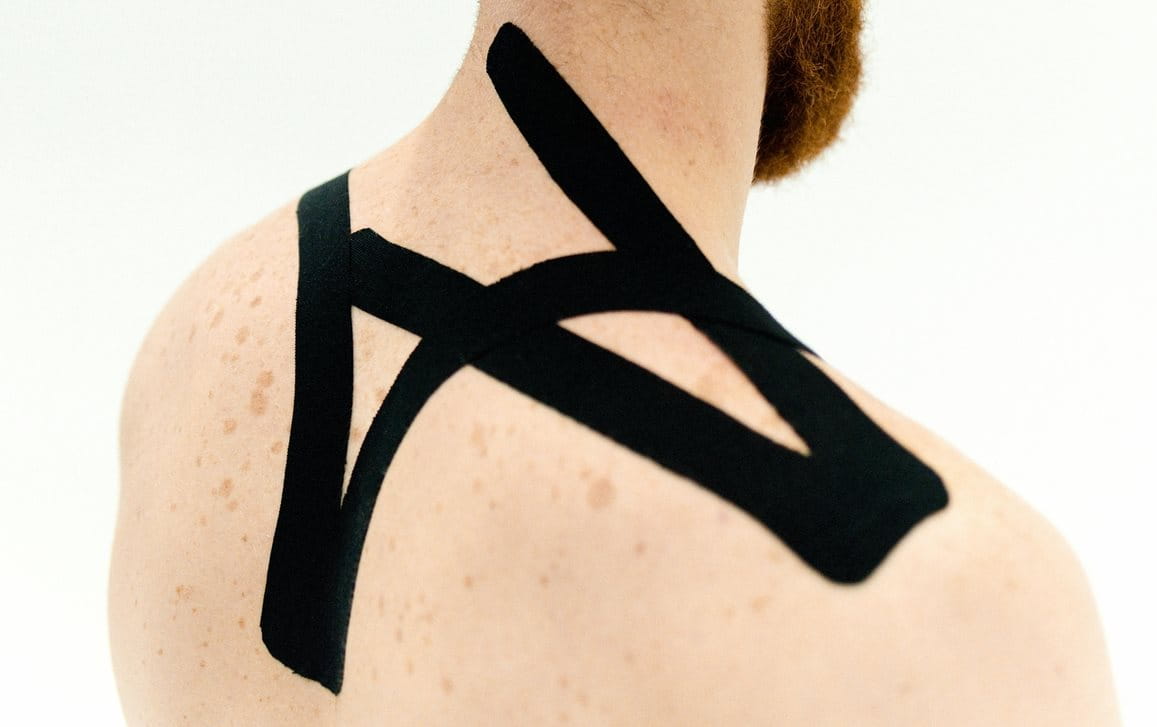 Mann mit schwarzem Kinesiologie Tape im Nacken.