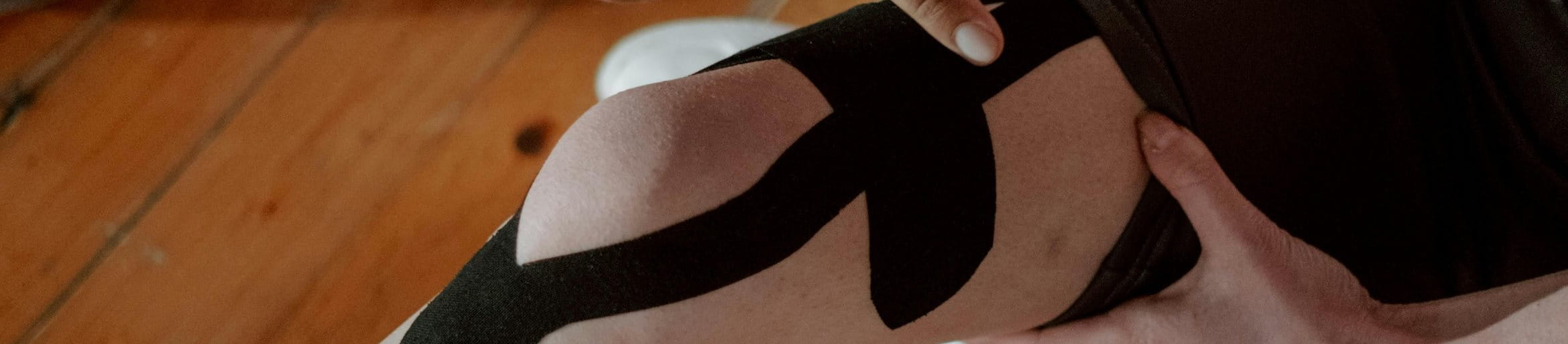 Knie werden mit schwarzem und pinkem Sportband beklebt.