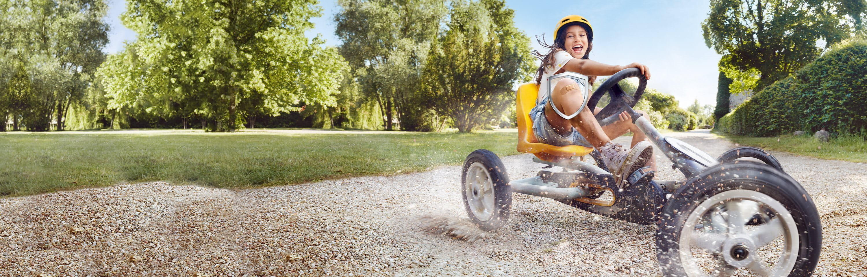 Kind fährt mit einem Pflaster auf dem Knie Go-Kart