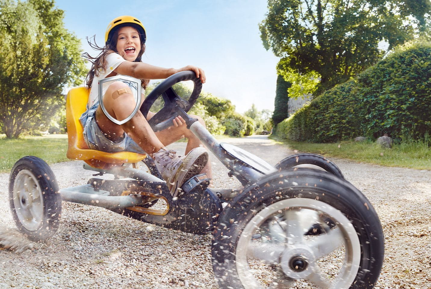 Kind fährt mit einem Pflaster auf dem Knie Go-Kart
