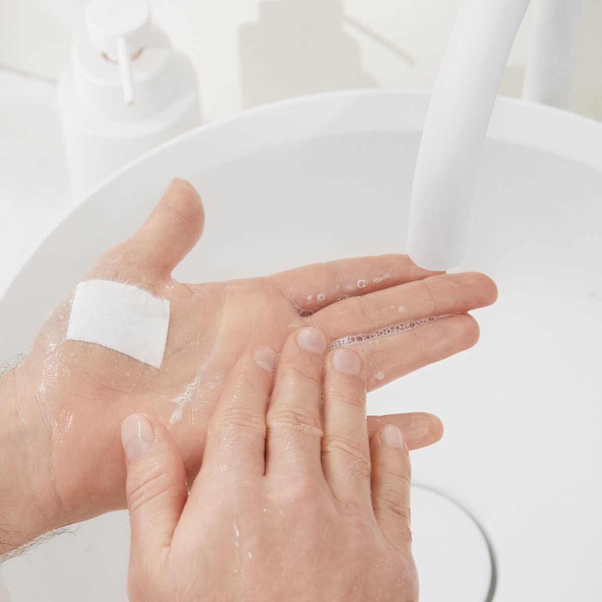 Hand mit Pflaster unter fließendem Wasser