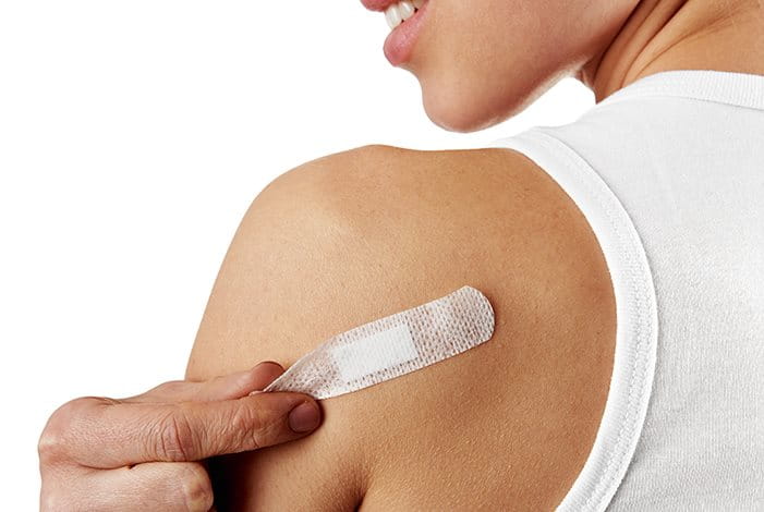 Eine junge Frau entfernt ein Pflaster