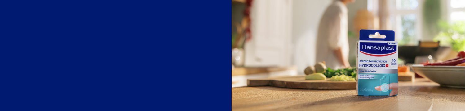 A grandmother is smiling while holding her grandchild. Parts of her right forearm are covered with a Hansaplast Ultra Sensitive Plaster in the new XXL size.
