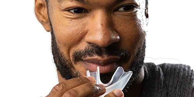 Person preparing to insert a clear, transparent mouthguard.