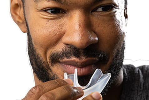 Person preparing to insert a clear, transparent mouthguard.