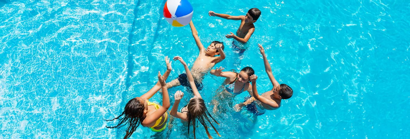 Kinder spielen im Schwimmbad mit einem bunten Ball
