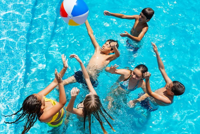 Kinder spielen im Schwimmbad mit einem bunten Ball