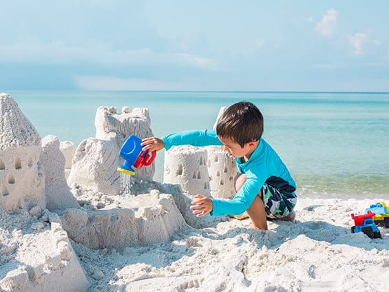 Ein Kind baut eine Sandburg am Strand