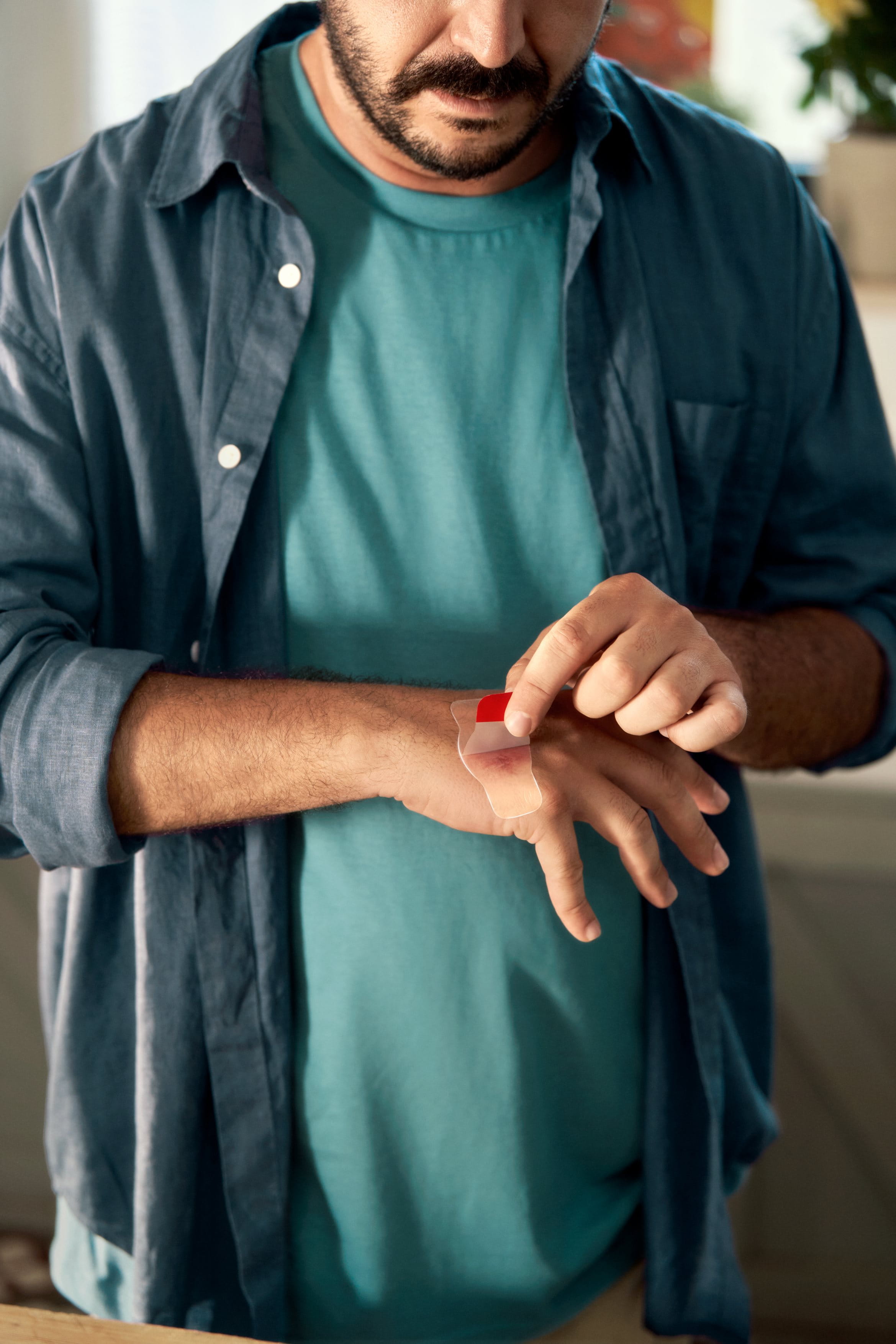 man applying plaster to wound